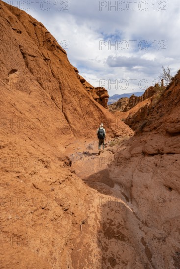 Mountaineers in a canyon with a dry stream bed, eroded mountain landscape with red sandstone rocks, rock formations, Konorchek Canyon, Chuy, Kyrgyzstan