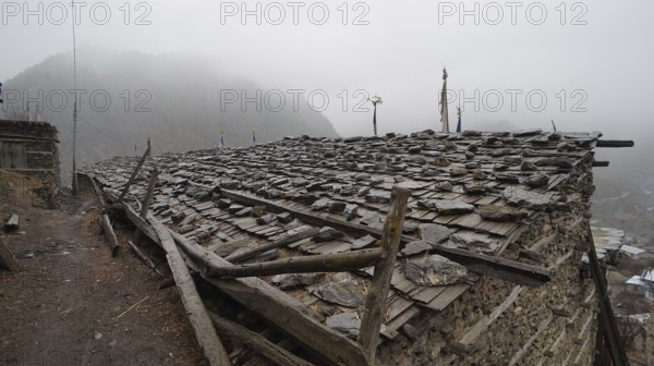 Stone roof of an old building in a foggy mountain village, trekking at Annapurna Circuit, Manang, Nepal