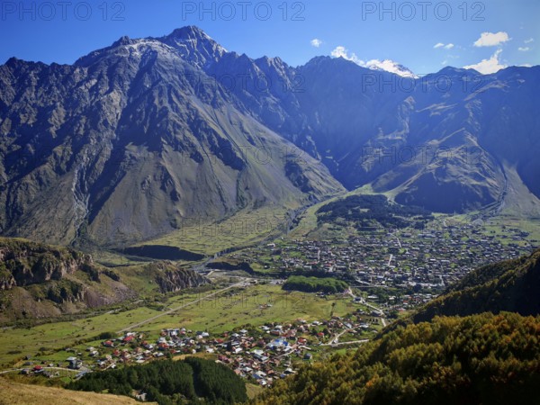 Panorama of a valley with a city and dramatic mountain ranges, Stepantsminda, Caucasus, Georgia