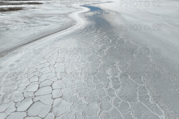 A mesmerizing aerial view of a saline mud landscape, showcasing intricate natural patterns and textures in earthy hues. The serene, cracked surface adds a unique visual appeal