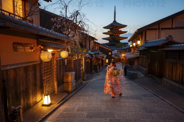 Japanese woman wearing kimono in an alley, Yasaka dori historic alleyway in the old town with traditional Japanese houses, five-story Yasaka pagoda of the Buddhist Hokanji Temple in the back, Higashiyama, Kyoto, Japan