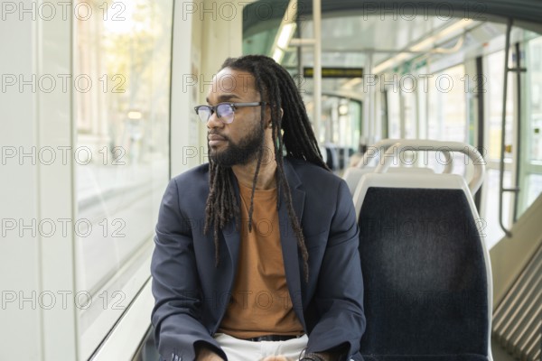 A cuban business man sits thoughtfully on a modern tram, gazing out the window. The serene atmosphere of public transport provides a moment of reflection during his commute