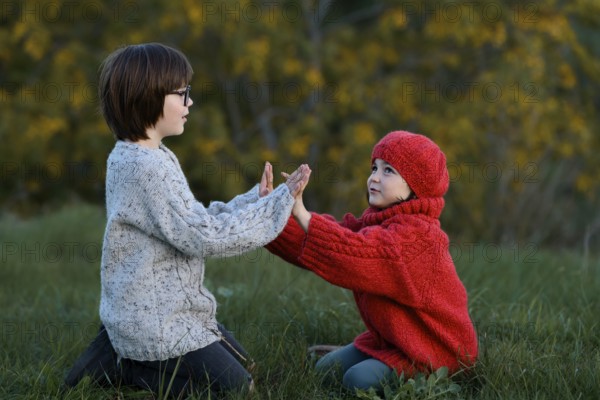 A boy and a girl enjoying a playful moment together in a vibrant autumn park setting, surrounded by yellowing trees and crisp, fall air
