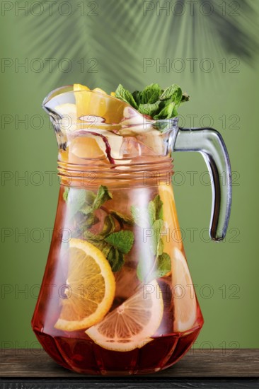 Pitcher with cold citrus sangria over green background