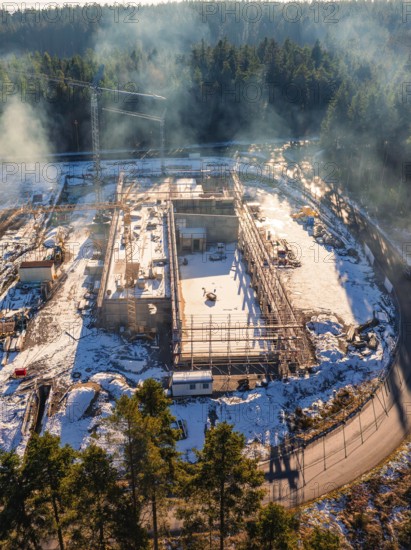 Snow-covered construction site with scaffolding and crane in the wintry forest, new fire station, Oberhaugsett, Calw district, Germany