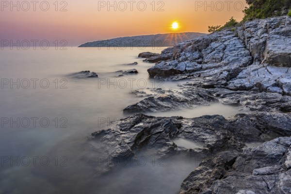Sunset over crystal clear water on the beach of Ustrine Bay on the island of Cres, long exposure, Croatia