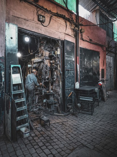 Small, dark workshop full of cables and metal in the Medina with craftsmen at work, atmospheric lighting, nostalgic atmosphere, Morocco