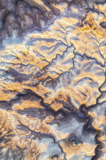 Aerial capture of Utah's stunning golden bentonite formations, showcasing their unique patterns and textures. The sun casts a warm glow, highlighting natural beauty