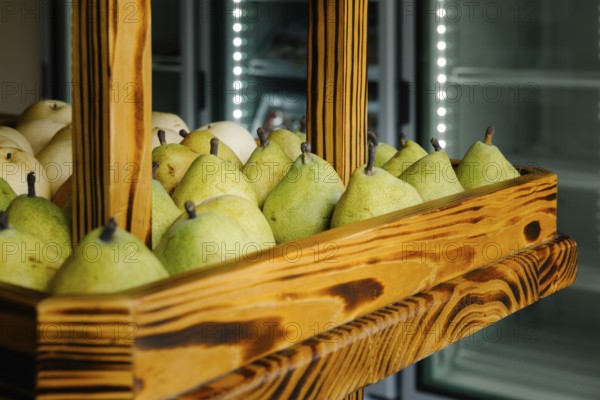 Fresh green pears neatly arranged in a rustic wooden display case at a market in Tulum, Mexico. The vibrant fruit contrasts beautifully with the smooth wooden texture, evoking a sense of local charm and natural abundance