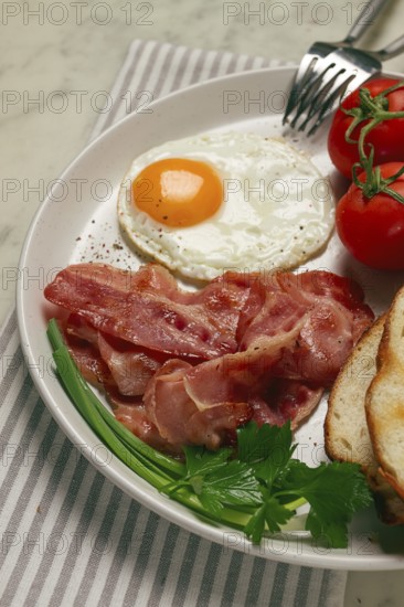 Breakfast, fried egg, bacon and bread, with cherry, on a light background, homemade, no people