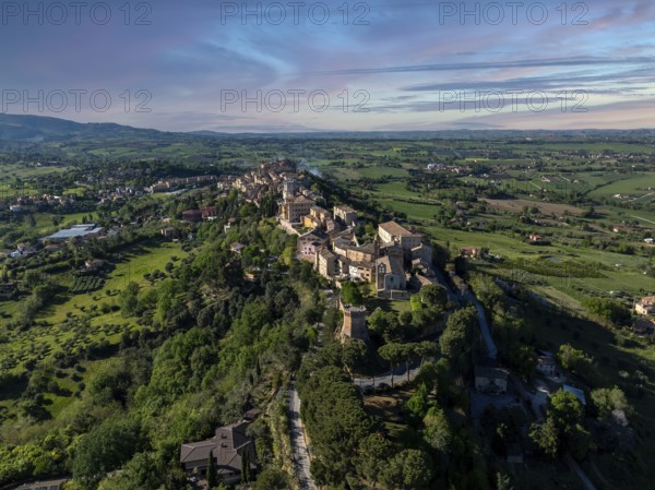 Breathtaking aerial view of Treia, Italy, showcasing historic architecture amid lush greenery and rolling hills under a clear blue sky, capturing the essence of Italian charm