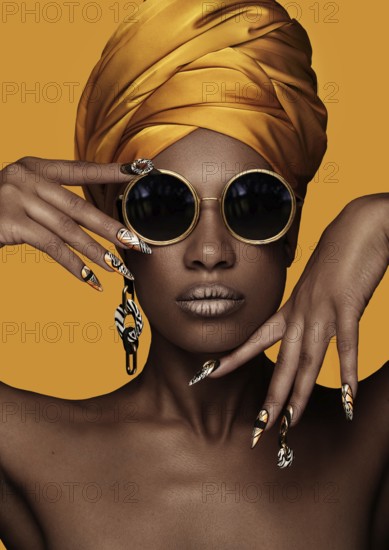 Beautiful black woman with a yellow towel on her head, classic makeup and art manicure. Beauty face. Photo taken in the studio