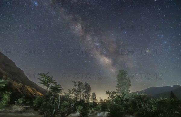 A breathtaking view of the Milky Way galaxy stretching above the serene landscape of Sequoia National Park, captured on a clear, star-filled night