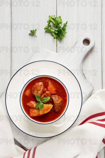 Potatoes stewed with meat, in tomato sauce, with spices and herbs, no people, on a white table