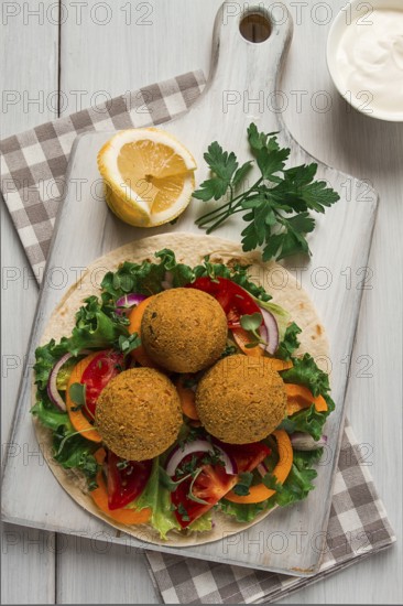 Tortillas, wrapped falafel balls, with fresh vegetables, vegetarian healthy food, on a wooden white background, no people, selective focus