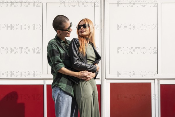 A Colombian lesbian couple shares a tender moment, embracing against a modern backdrop. This image captures love, diversity, and unity within the LGBTQIA+ community