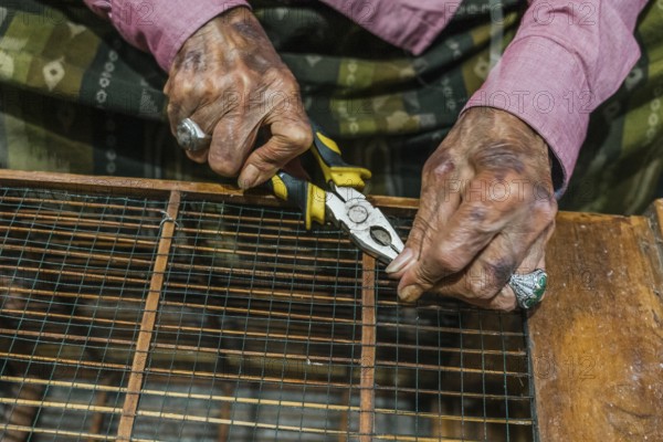 Close up of balinese hands using pliers to craft with wire. The image captures the essence of craftsmanship and handiwork, focusing on traditional skills and tools