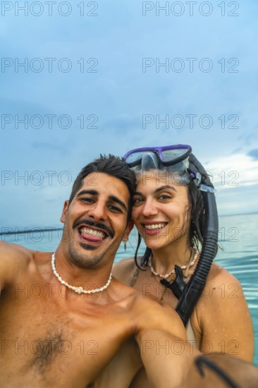 Couple taking a selfie with snorkeling gear in the ocean at white beach, cebu island, philippines, enjoying their tropical vacation