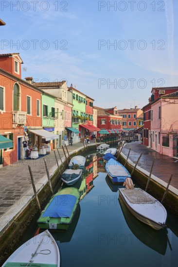 Colorful houses beside the waterway in between 'Fondamenta San Mauro' and 'Fondamenta degli Assassini' with boats lying in the water on the island of Burano, Italy
