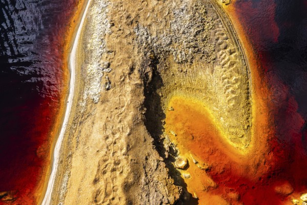 Aerial view of the vibrant red and orange hues along the banks of the Riotinto in Huelva, Spain, showcasing its unique mineral-rich waters and dramatic landscape