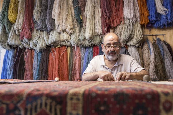 An Iranian master skillfully restores rare carpets in his well-equipped workshop in Salzburg, Austria, surrounded by colorful yarns