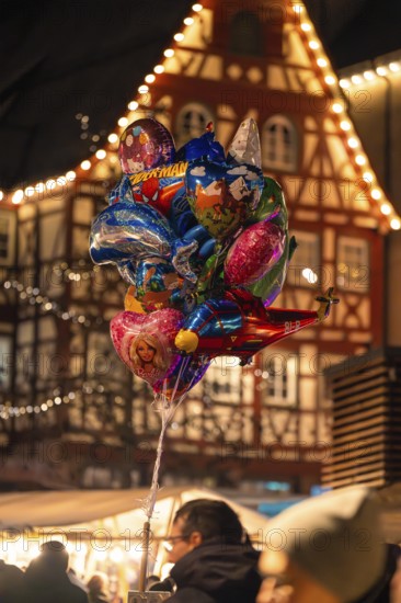 A colourful collection of balloons in front of traditional architecture at a lively Christmas market, Christmas market Calw, Black Forest, Germany