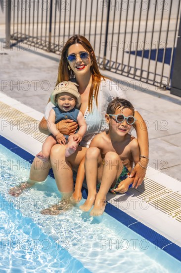 Vertical portrait of a happy family of a caucasian mother and two child in the swimming pool