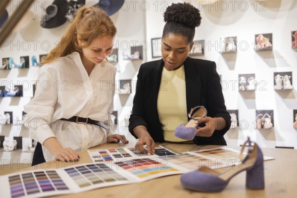 Two women discuss color options for footwear in a bridal studio. They review a color palette and shoe samples, focusing on creativity and fashion trends