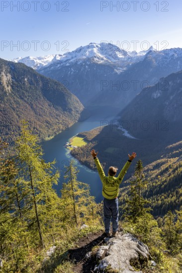 Mountaineer stretches his arms in the air, viewpoint Archenkanzel, panoramic view of the Königssee, autumn forest and snow-covered mountains, Berchtesgaden National Park, Berchtesgadener Land, Upper Bavaria, Bavaria, Germany