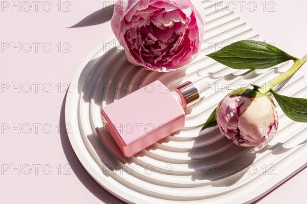 A pink cosmetic bottle is elegantly placed on a white decorative tray, surrounded by beautiful pink peonies. The sunlight enhances the subtle aesthetics of the scene