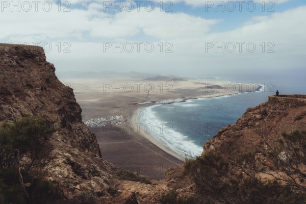 A stunning view of Lanzarote's rugged cliffs and expansive coastline, with waves crashing against the shore and a vast sky above, capturing the island's natural beauty
