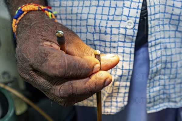 Close-up of a hand with a colored bracelet holding a small object, the gemstone cutters in the city of Ratnapura in Sri Lanka