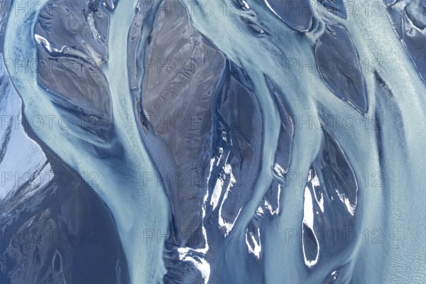 Stunning aerial drone photograph showcasing the complex, natural river patterns and icy textures along the coastline of Iceland. The image captures the serene beauty and unique geological formations typical of Icelandic landscapes