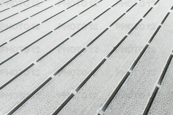 Close-up view of geometric salt formations at Salinas Grandes in Salta, Argentina. The surface displays linear patterns and natural salt crystal textures creating abstract symmetry