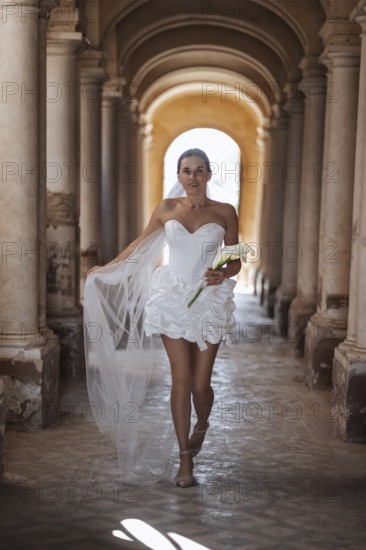 A bride in a stunning white gown gracefully walks down the aisle of the ancient villa in Treia, Macerata. The setting captures the timeless elegance of an Italian wedding