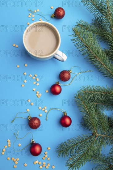 Christmas or New Year composition. Decorations, red balls, fir and spruce branches, cup of coffee, on a blue paper background. Top view, close up, flat lay