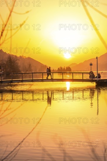 People on a bridge over a lake at sunset with intensive reflection, Großer Alpsee, Immenstadt im Allgäu, Bavaria, Germany