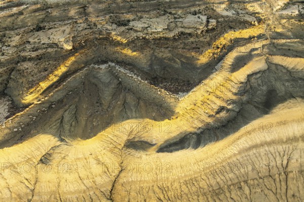 Aerial view of Utah's golden sandstone desert displaying intricate patterns and rich textures. The rugged landscape reveals nature's artistry and geological history