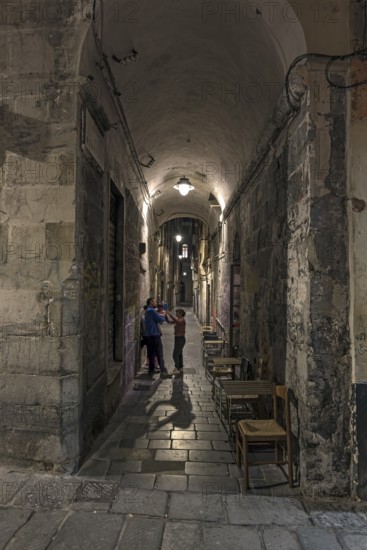 Young family in an old town alley in the evening, Genus, Italy