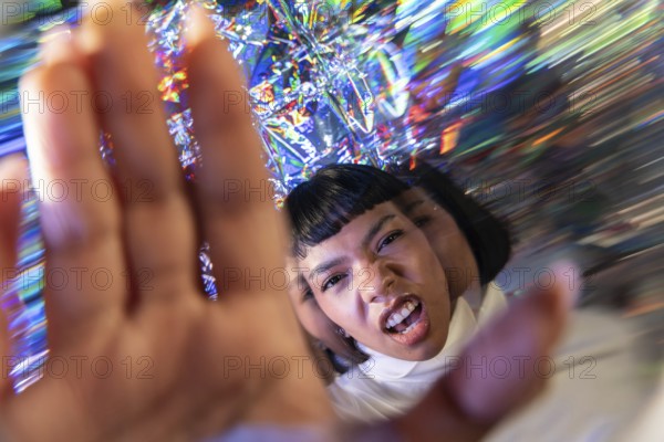 A futuristic Latin woman engages with the vibrant and dynamic digital world of the metaverse, surrounded by a kaleidoscope of vivid colors and holographic reflections