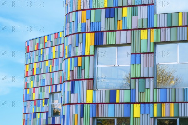 A stunning view of a modern building's curved facade adorned with multicolored panels. Bright blues, yellows, reds, and greens create a visually captivating pattern