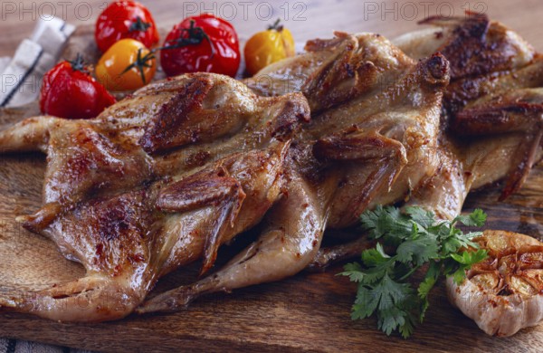 Grilled quail meat, on a wooden chopping board, tobacco, in the oven, with spices, homemade, without people