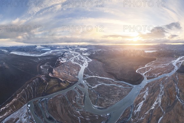 Aerial view of Iceland's highlands, showcasing intricate river networks weaving through rugged terrain at sunset. A breathtaking example of nature's artistry