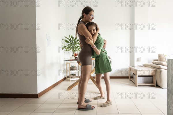 A touching moment between a young girl with a tracheostomy and her supportive sister, captured in a warm home setting, conveying love, inclusion, and familial support in overcoming challenges