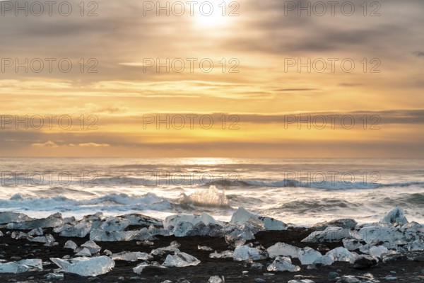 Captivating sunrise over Diamond Beach, Iceland, with ice fragments glistening on black sands and waves crashing gently, capturing the essence of serene Arctic beauty