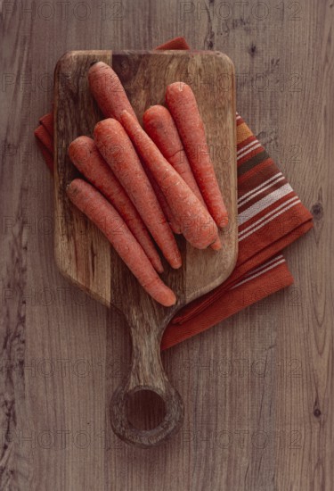 Fresh carrots on a chopping board, wooden table, raw carrots, no people