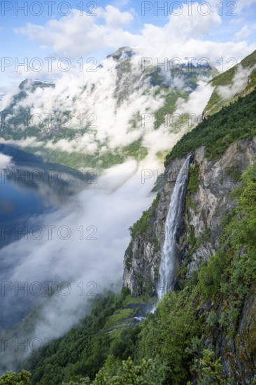 Gjerdefossen waterfall, at Ørnesvingen viewpoint, atmospheric clouds over the fjord in the morning light, at Geirangerfjord, near Geiranger, Møre og Romsdal, Norway