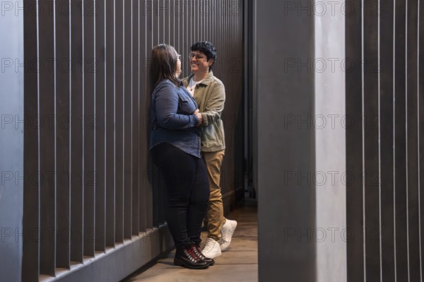A lesbian couple shares a tender moment in an urban setting, expressing love and connection. The modern backdrop highlights their affection and vibrant interaction