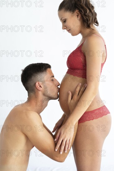 A couple sharing an intimate moment, highlighting the beauty of pregnancy The man kisses the woman's baby bump, symbolizing love, anticipation, and the journey of parenthood