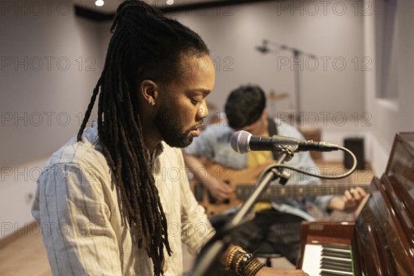 Two musicians immerse themselves in crafting music in a recording studio. One plays the piano while the other accompanies on guitar, each focused on creating harmonious melodies